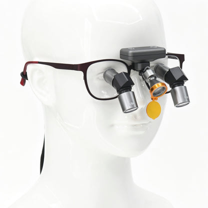 Front wearing view of wireless dental LED headlight attached to ergonomic loupe frame on medical mannequin model